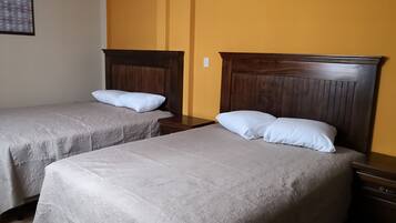 Two single beds with wooden headboards in a room with yellow walls.