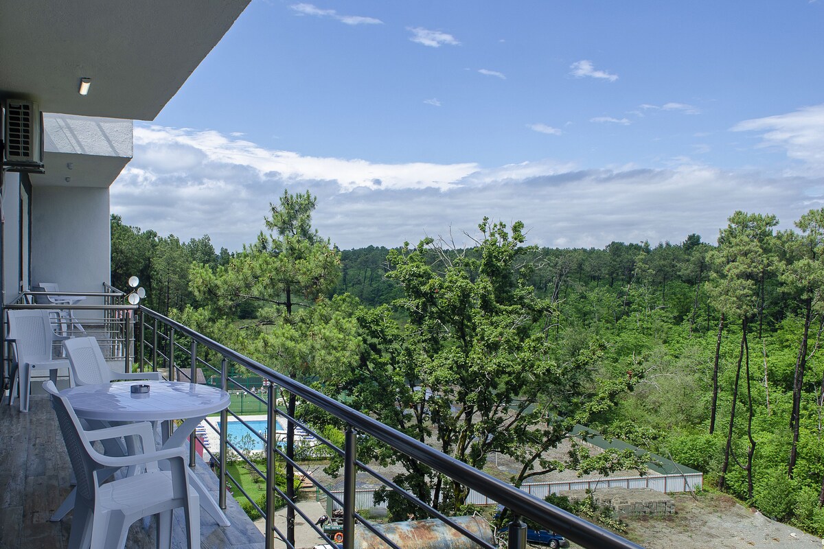 A balcony with a pool, surrounded by lush greenery and trees.