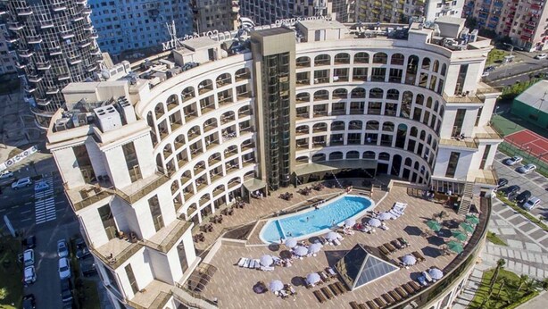 A hotel with a central courtyard featuring a swimming pool, multiple balconies, and a tennis court. - Batumi Real Lux (Batumi)