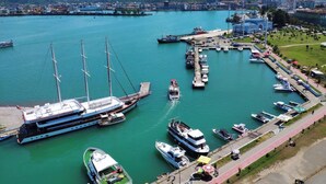 A marina with various boats docked, a large cruise ship, and a cityscape in the background. - Batumi Real Lux (Batumi)