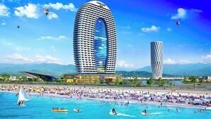 A modern hotel with a curved facade, a pool area with numerous sun loungers, and a view of the surrounding landscape. - Batumi Real Lux (Batumi)