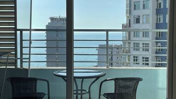 A balcony with a view of the sea and adjacent buildings.