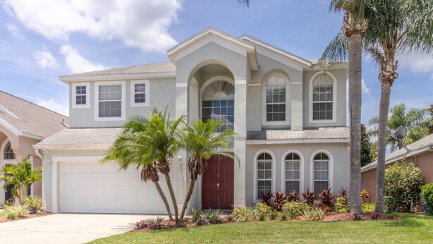 A two-story house with a garage, arched windows, and a well-maintained lawn. - SEASONAL LOW RATES!!!Located in Disney's backyard- WITH PRIVATE POOL!!! (Clermont)