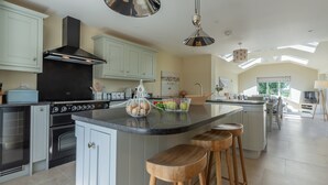 A modern kitchen with a central island, built-in ovens, and a large window providing natural light.