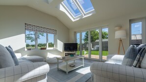 A spacious living room with a high ceiling, a television, and a comfortable seating area.
