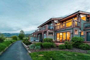 A two-story house with a covered porch, a driveway, and a view of the surrounding landscape.