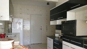A kitchen with white cabinets, a black countertop, and a built-in oven. - There's still time to make your reservation for Carnival, excellent apartment, take advantage! (Cabo Frio)