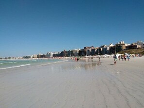 A wide sandy beach with buildings in the background. - There's still time to make your reservation for Carnival, excellent apartment, take advantage! (Cabo Frio)