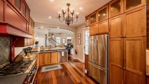 A spacious kitchen with wooden cabinets, a stainless steel refrigerator, and a gas stove.