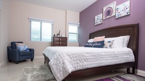 A bedroom with a bed, a chair, a dresser, and a window.