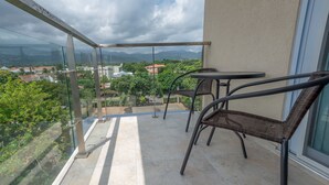 A balcony with a glass railing, two wicker chairs, and a small table.