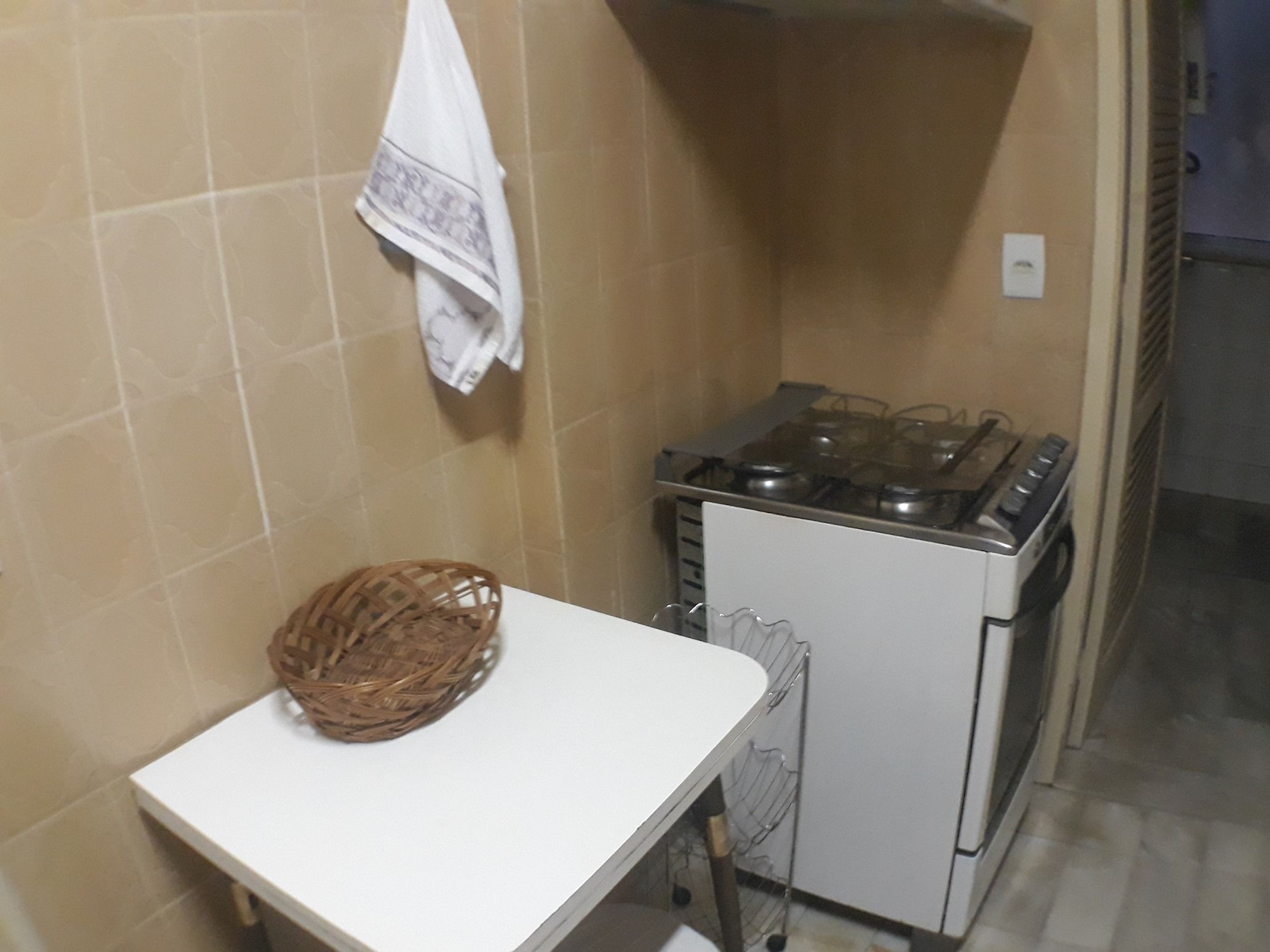 A kitchen with a stove, a white countertop, and a woven basket.