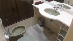 Une salle de bain équipée de toilettes, d’un bidet et d’un lavabo avec un miroir.