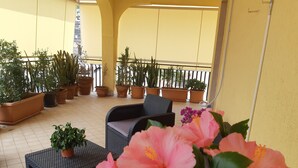 Un balcon agrémenté de plantes en pot, une chaise en osier et une table.