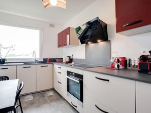 A modern kitchen with white cabinets, a built-in oven, a sink, and a window. - Port An Dro by Interhome (Carnac)
