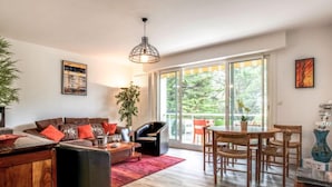 A spacious living room with a large window, a dining area, and a cozy seating area. - Port An Dro by Interhome (Carnac)