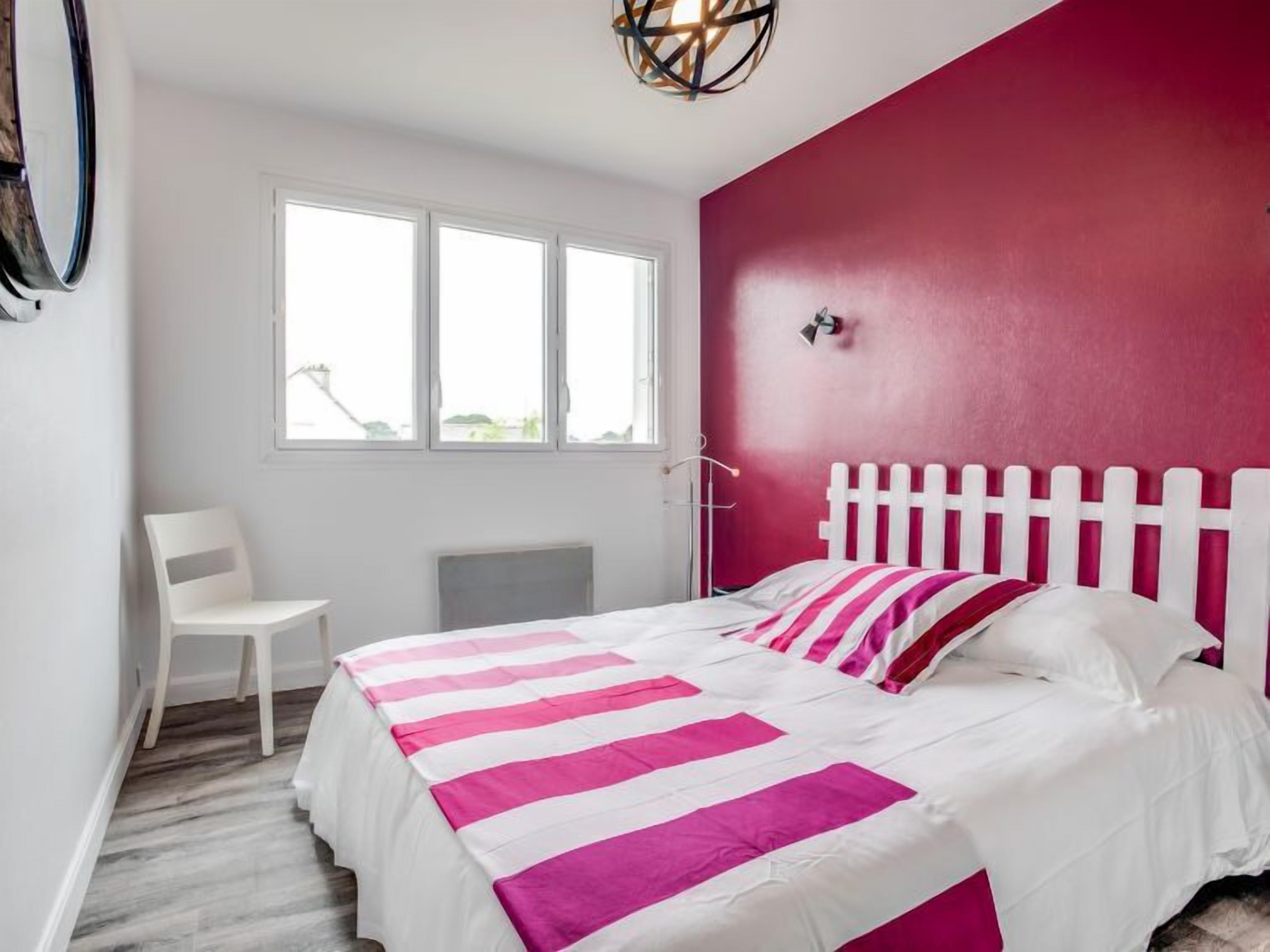 Un dormitorio con cama, una silla y una ventana.