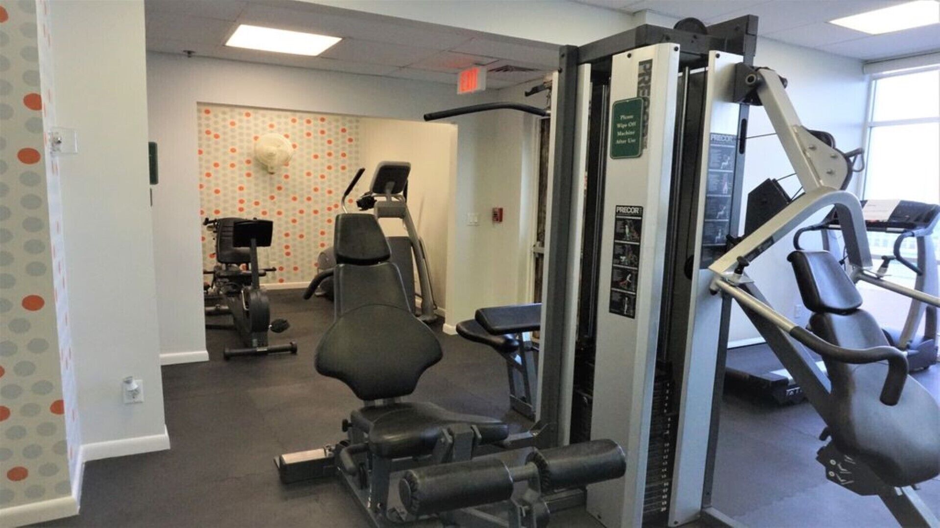 A gym with a variety of exercise equipment including a weight machine, a bench, and a treadmill.