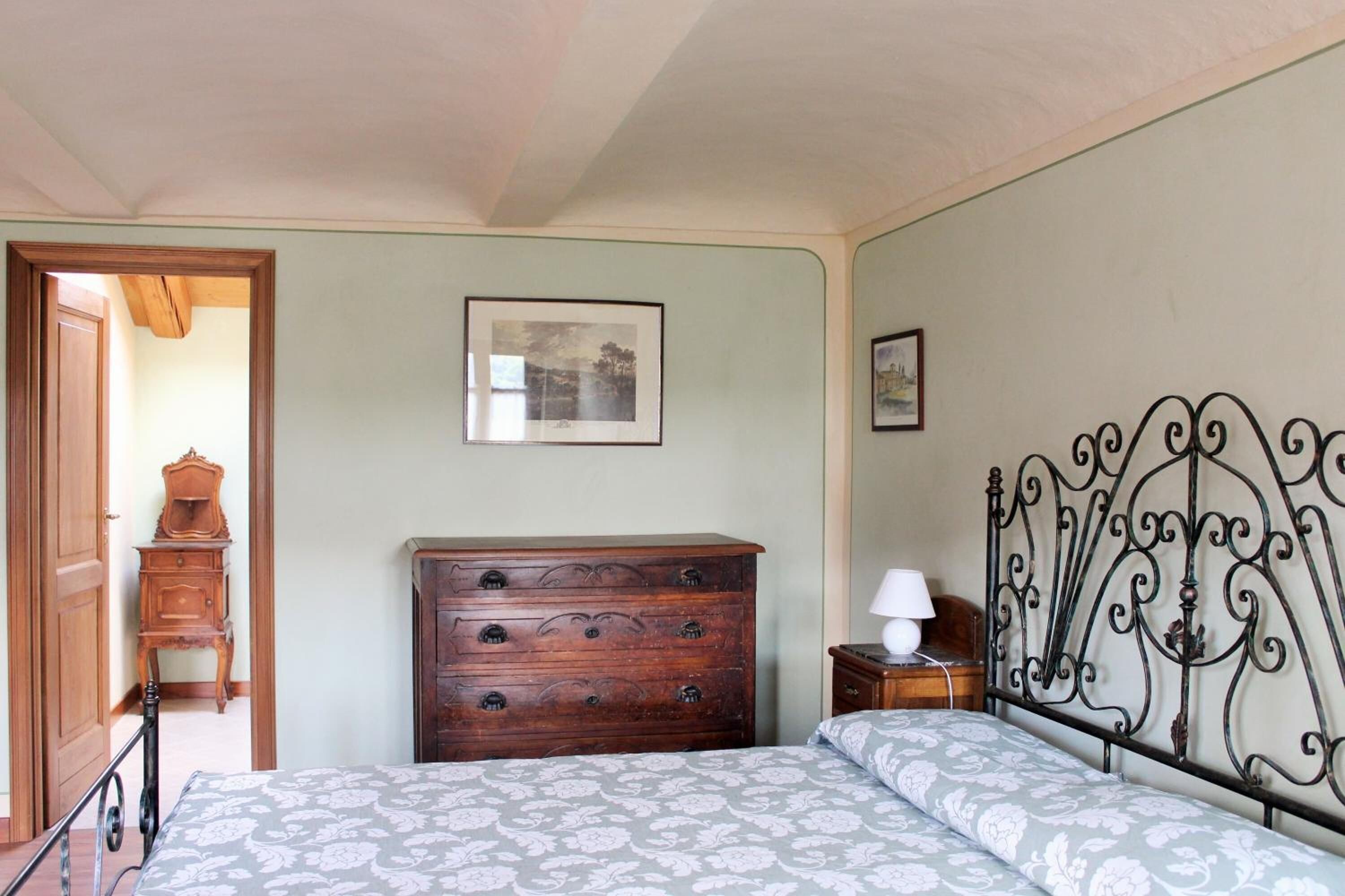 A bedroom with a bed, wooden dresser, and a metal headboard.