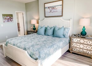 A bedroom with a bed, two nightstands, a dresser, and a framed picture on the wall.