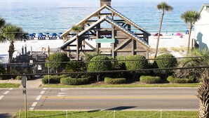 A wooden structure with a sign reading "Emerald Shores" overlooking a beach with umbrellas and palm trees.