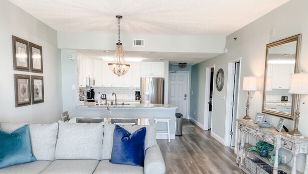 A modern living room with a grey sofa, a coffee table, and a chandelier.