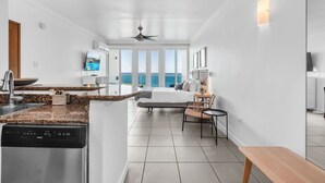 A modern hotel room with a kitchen, a dining area, and a large window offering a sea view. - Oceano Studio  | Oceanfront Studio with Kitchen in Trendy Condado Location (San Juan)