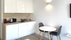A modern kitchen with white cabinets, a wooden countertop, a sink, and a small dining area with two chairs and a table. - Studio with terrace on the Croisette - Residence du Grand Hotel (Cannes)