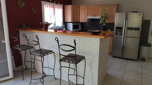 A kitchen with a central island, bar stools, a refrigerator, a microwave, and a sink. - Close to center, comfort room in air-conditioned villa sauna, billiard, garden (Perpignan)