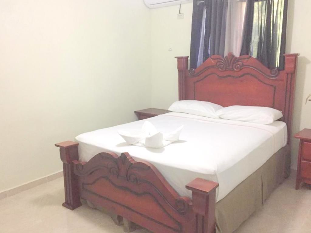 Una cama individual con cabecera y piecera de madera, una mesita de noche y un espejo en la pared.