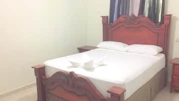 Una cama individual con cabecera y piecera de madera, una mesita de noche y un espejo en la pared.