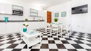A modern kitchen with white cabinets, a black and white checkered floor, a dining area with a white table and chairs, and a ceiling fan. - Mint Suite | 1BR Apt at Old San Juan (San Juan)