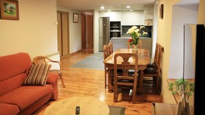 A living room with a sofa, a coffee table, and a dining table with chairs. There is a kitchen in the background. - ARTXEA RURAL HOUSE 1PLTA (Mardea)