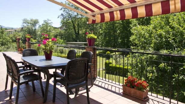 A patio with a table and chairs, surrounded by potted plants and a railing overlooking a garden. - ARTXEA RURAL HOUSE 1PLTA (Mardea)