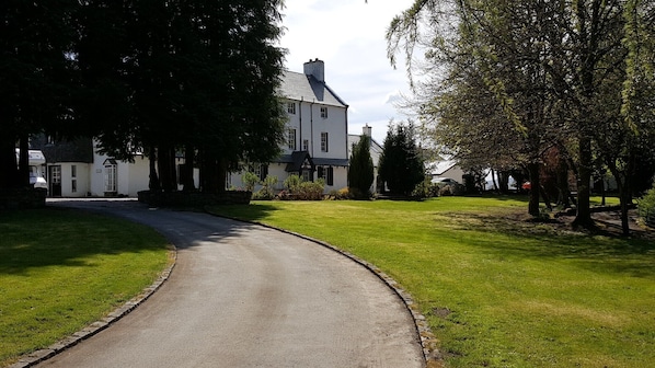 A two-story white building with a dark roof, surrounded by well-maintained grass and trees.