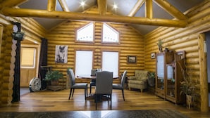 A log cabin interior with a dining area, two windows, a fan, and a cabinet. - Modern log home with a view of the Tetons! (Victor)