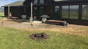 A log cabin with a patio, outdoor seating, a grill, and a fire pit. - Modern log home with a view of the Tetons! (Victor)