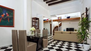 Uma sala de estar moderna com piso xadrez, uma mesa de jantar de vidro e um sofá bege.