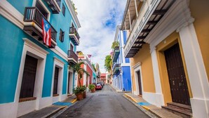 Rua estreita ladeada por edifícios coloridos, cada um com varandas e vasos de plantas.