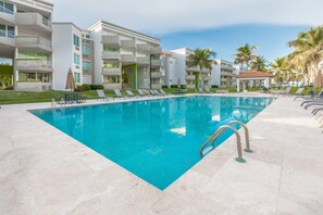 A swimming pool with lounge chairs and a building with balconies in the background.