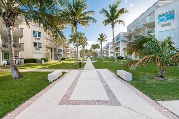 A resort with multiple-story buildings, palm trees, and a central pathway.