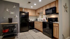 A modern kitchen with wooden cabinets, a black refrigerator, a microwave, a stove, and a coffee maker. - INDOOR POOL! CLOSE TO DOLLYWOOD!! (Pigeon Forge)