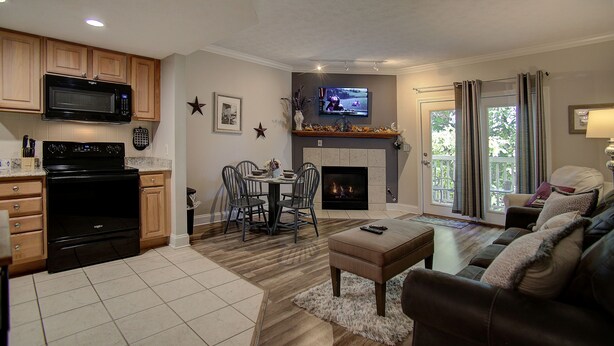 A modern living room with a fireplace, a television, and a dining area with chairs and a table. - INDOOR POOL! CLOSE TO DOLLYWOOD!! (Pigeon Forge)