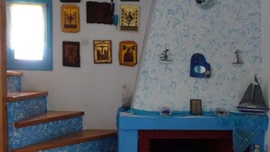 Een trap met blauw geschilderde treden die leidt naar een kamer met een open haard, een raam en verschillende ingelijste foto's aan de muur.