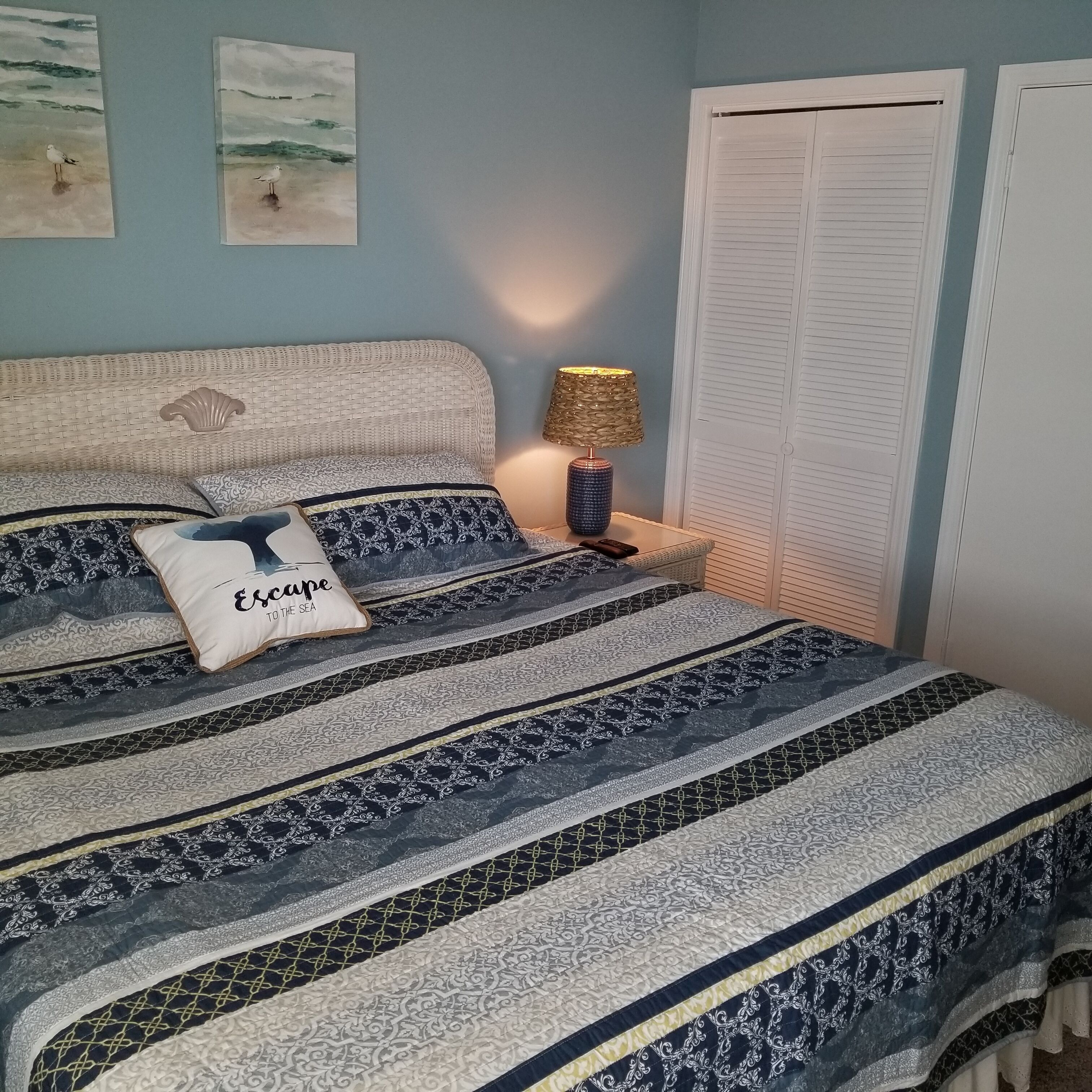 Une chambre à coucher avec un lit, une table de chevet, une lampe et une porte.
