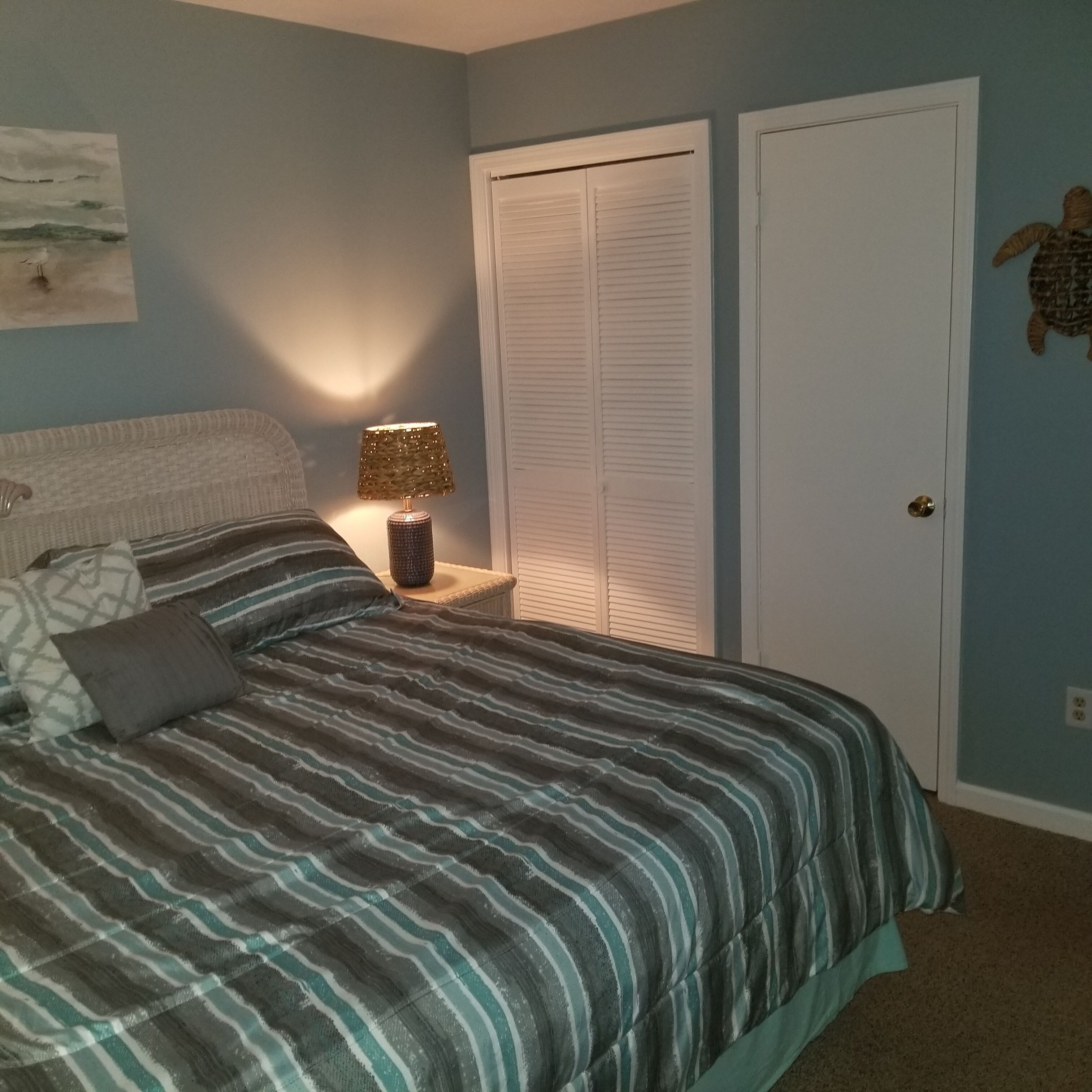 Ein Schlafzimmer mit einem Bett, einem Nachttisch, einer Lampe, einem Kleiderschrank und einer Wanddekoration.