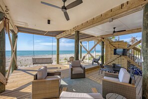 A wooden deck with wicker furniture, a swing, and a TV screen.