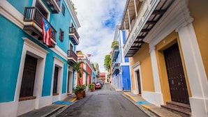 A narrow street lined with colorful buildings, each with balconies and potted plants. - Azure Suite | 1 BR Apt at Old San Juan (San Juan)