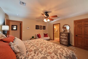 A bedroom with a bed, a ceiling fan, a dresser, and a door leading to another room. - Gateway Gathering - Cabin I Fredericksburg, stargazing (Fredericksburg)