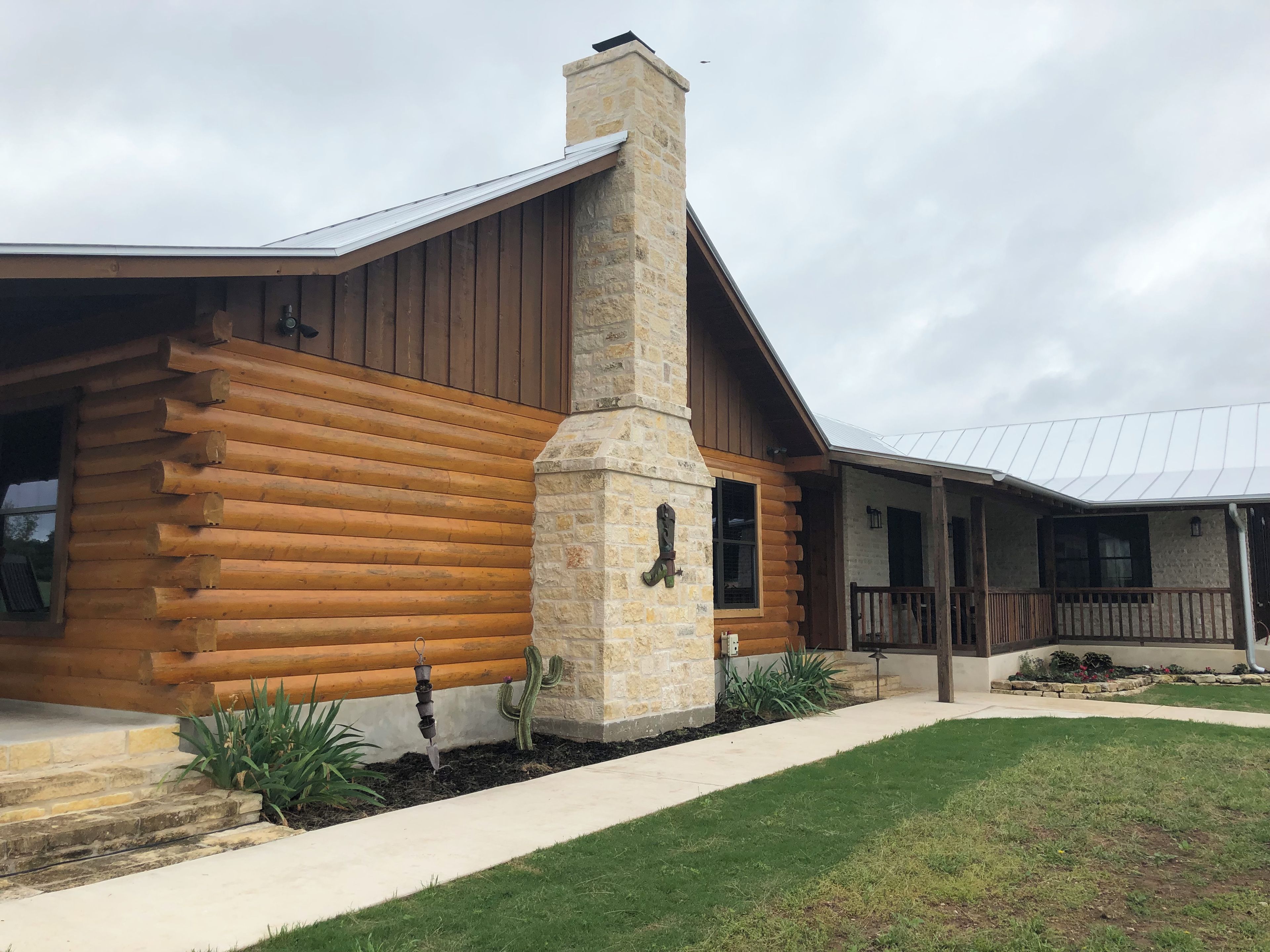 A log cabin-style building with a stone chimney, wooden exterior, and a covered porch.